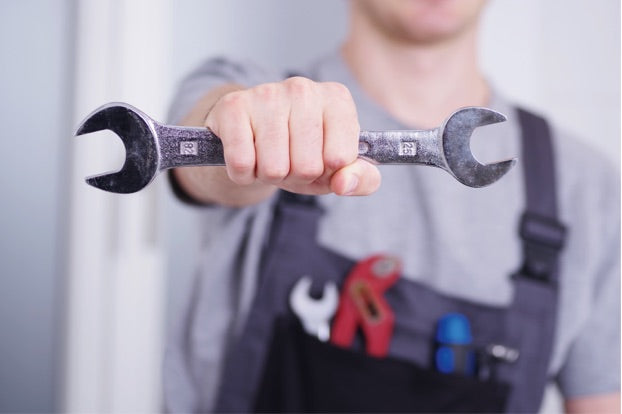 Ein Handwerker hält einen Maulschlüssel.